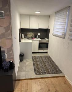 una pequeña cocina con armarios blancos y alfombra en MG Sa, en Sarajevo