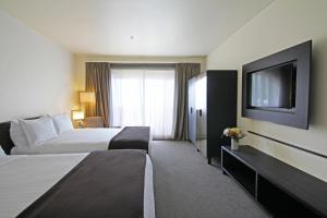 a hotel room with two beds and a flat screen tv at Hanmer Springs Hotel in Hanmer Springs