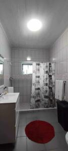 a bathroom with a shower and a red rug at Apartamento da Matilde in Santa Cruz das Flores