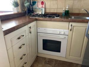 a kitchen with white cabinets and a white stove top oven at Acogedor Departamento amoblado Viña del Mar Poniente 2D 1B in Viña del Mar +3 photos