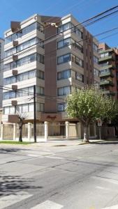 a tall building with a tree in front of it at Acogedor Departamento amoblado Viña del Mar Poniente 2D 1B in Viña del Mar