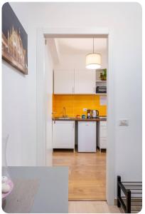 a kitchen with white cabinets and a yellow wall at Casa Rizzoli - bilocale vicinissimo M2 in Milan