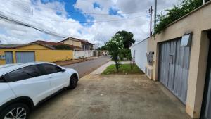 ein weißes Auto, das am Straßenrand geparkt ist in der Unterkunft Quitinete Ar Condicionado WIFI Garagem Individual in Goiânia