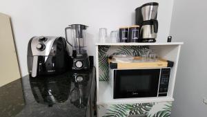 a kitchen with a microwave and a coffee maker at Quitinete Ar Condicionado WIFI Garagem Individual in Goiânia