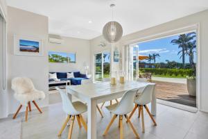 a white dining room with a white table and chairs at Estuary Bliss Getaway in Mangawhai