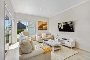a living room with a couch and a table at Estuary Bliss Getaway in Mangawhai