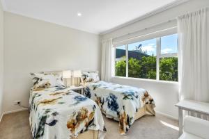a bedroom with two beds and a window at Estuary Bliss Getaway in Mangawhai