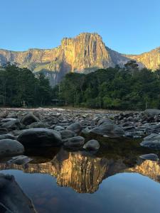 un reflejo de montaña en el agua con rocas en Kiapok Canaima, en Canaima