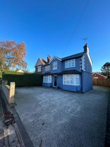 a blue house with a large driveway at 4 bed private home in Colchester in Colchester
