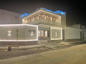 a large white building with blue lights on it at شاليه رحال in Yanbu Al Bahr