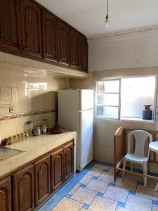 a kitchen with wooden cabinets and a white refrigerator at Appartement meublé sans vis à vis proche de toutes commodités 5 min à Marjane chaikh Zaid et centre ville in Khouribga