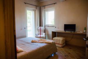 Agriturismo Bellarosa في Albinea: غرفة نوم بسرير ومكتب وتلفزيون
