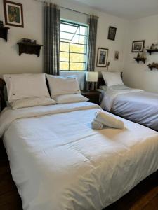 1 dormitorio con 2 camas con sábanas blancas y ventana en Habitación Privada en Mongui, en Monguí