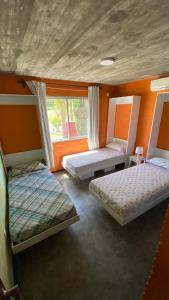 3 camas en una habitación con paredes de color naranja en Ampakiti Home, en Punta del Este