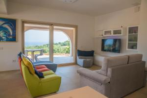 sala de estar con sofá, sillas y ventana en Villa Dune di Scivu, en Portixeddu