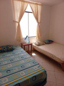 2 camas en una habitación con ventana en Departamento de verano - CAMANA, en Camaná