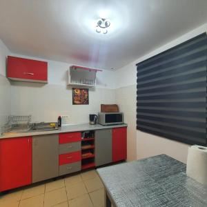 a kitchen with red cabinets and a microwave at Apartament Atoosa cu vedere la munte in Sinaia