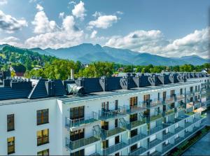 un edificio de apartamentos con balcones y montañas en el fondo en Mountains & SPA Apartament Zakopiański en Zakopane