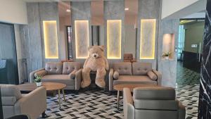 un grand ours en peluche assis dans une salle d'attente dans l'établissement โรงแรมเซเว่นรัชดา S7VEN RATCHADA, à Ban Na Song