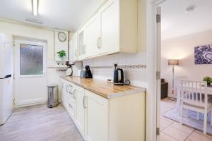 cocina con armarios blancos y encimera de madera en 4 Bedroom High Wycombe Home With Free Parking Free WiFi Private Garden - Great Transport Links!, en Buckinghamshire
