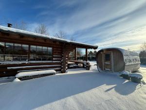 una cabaña con nieve en el suelo al lado en Fjordhygge - Authentic wood log cabin summerhouse near water, fjord and forest, en Jægerspris