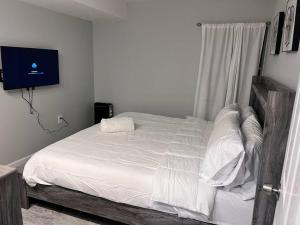 een slaapkamer met een bed met witte lakens en een televisie bij Spacious secluded Big 2 Kings near EWR/Newark Downtown in Newark