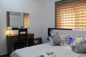 een slaapkamer met een bed, een bureau en een stoel bij KANS KRIB in Accra