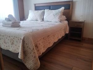 1 dormitorio con 1 cama con sábanas y almohadas blancas en Umantü Hostel, en Panguipulli