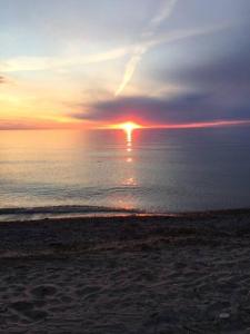 a sunset on the beach with the sun setting over the ocean at Steps to Beach, Fantastic Sunsets, Charming 3 bedroom Cottage in Ripley