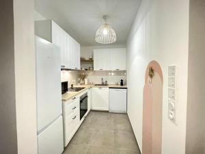 a kitchen with white cabinets and a pink door at Bohemian Lodge Near Paris 8P Metro 14 in Saint-Ouen