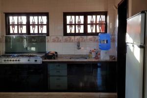 a kitchen with a sink and a stove and windows at Casa Rio das Ostras in Rio das Ostras