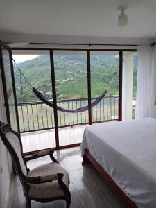 a bedroom with a bed and a large window at Hospedaje Rural Cabañas Mirador de la Cascada in Santa Rosa de Cabal