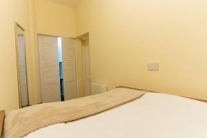 Schlafzimmer mit einem weißen Bett und einem Spiegel in der Unterkunft Charming One-bed Flat in Dagenham