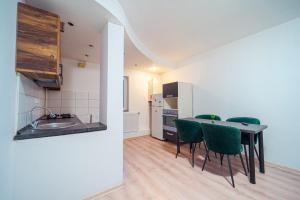 a kitchen and dining room with a table and green chairs at Hera's Bohemian Home in Arad