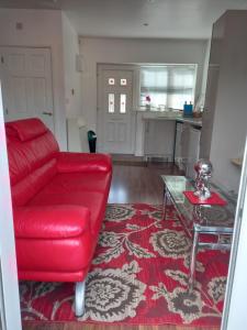 a living room with a red couch and a table at Colchester Town, modern, detached, guest house in Colchester