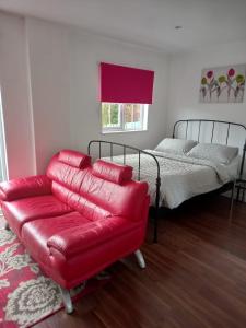 a living room with a red couch and a bed at Colchester Town, modern, detached, guest house in Colchester