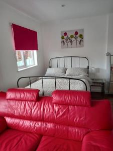 a living room with a red couch and a bed at Colchester Town, modern, detached, guest house in Colchester