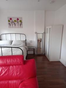 1 dormitorio con 1 cama y 1 sofá rojo en Colchester Town, modern, detached, guest house en Colchester
