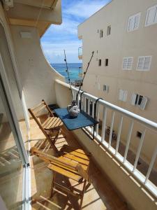 einen Balkon mit einem Tisch, Stühlen und Meerblick in der Unterkunft Formentera Suite 8 in Es Pujols
