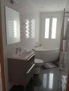 ein weißes Badezimmer mit einer Badewanne, einem WC und einem Waschbecken in der Unterkunft Appartement Cosy avec Jardin in Vaux-sur-Seine