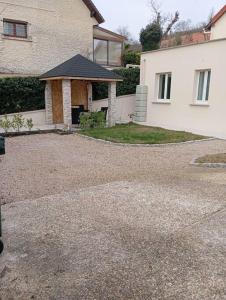 a house with a gravel driveway in front of it at Appartement Cosy avec Jardin in Vaux-sur-Seine