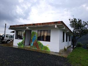 una pequeña casa con una pintura a un lado. en Hospedaje Rural Cabañas Mirador de la Cascada, en Santa Rosa de Cabal
