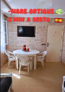 einen weißen Tisch mit Stühlen und einen TV an einer Ziegelwand in der Unterkunft soleil d'chamalo in Fnideq