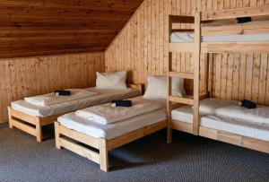 a room with three bunk beds in a cabin at Penzion a Restaurace Kamínek in Doksy