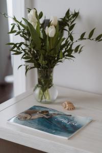 Eine Vase mit weißen Blumen und eine Zeitschrift auf dem Tisch in der Unterkunft Il Giardino della Tartaruga in Genua