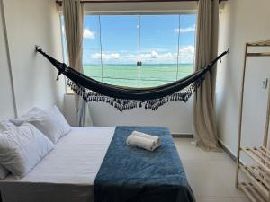 a bedroom with a hammock in front of a window at Paraiso Tropical a beira mar - WIFI 200MB - TV Smart - Cozinha equipada - Portaria 24h in Rio das Ostras