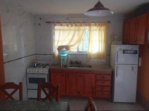 eine Küche mit einem Herd, einem Kühlschrank und einem Fenster in der Unterkunft Casa en Balcón de Mallín, Mirador del Lago in Bialet Massé + 16 Fotos