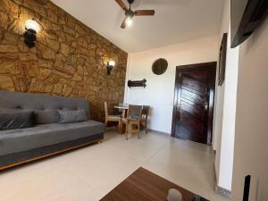 リオ・ダス・オストラスにあるApto Paradisíaco Beira Mar | ROMM108の石壁のリビングルーム(ソファ付)