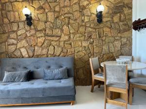 a living room with a couch and a stone wall at Paraiso Tropical a beira mar - WIFI 200MB - TV Smart - Cozinha equipada - Portaria 24h in Rio das Ostras