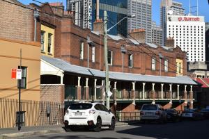 a white car parked in front of a brick building at Discover The Rocks - Historical Terrace House in Sydney